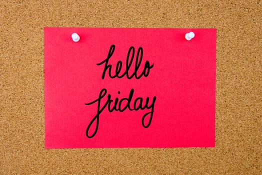 Red paper note with handwritten text Hello Friday pinned on cork board with white thumbtacks