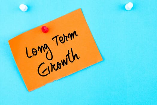 Long Term Growth written on orange paper note pinned on cork board with white thumbtack, copy space available