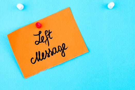 Left Message written on orange paper note pinned on cork board with white thumbtack, copy space available