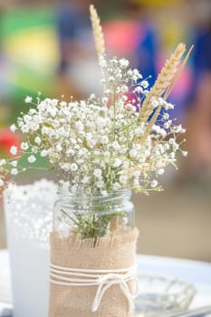 Flowers in mason jar with rope lace at an outdoors celebration