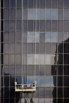 Window cleaners stand in an elevator and clean the windows of a high-rise building.