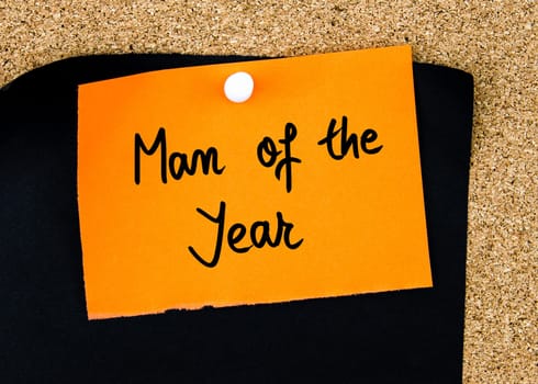 Man Of The Year written on orange paper note pinned on cork board with white thumbtacks, copy space available