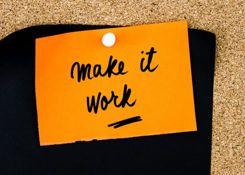 Make It Work written on orange paper note pinned on cork board with white thumbtacks, copy space available
