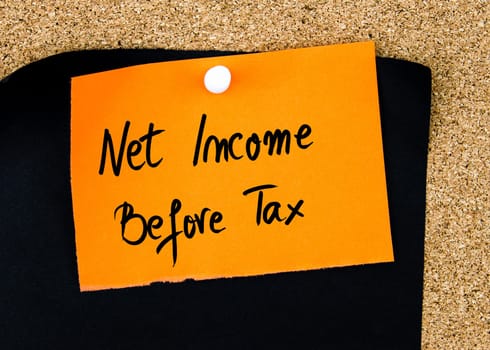 Net Income Before Tax written on orange paper note pinned on cork board with white thumbtacks, copy space available