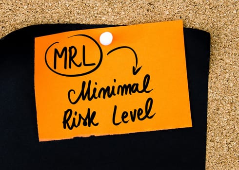 Business Acronym MRL as Minimal Risk Level written on orange paper note pinned on cork board with white thumbtacks, copy space available