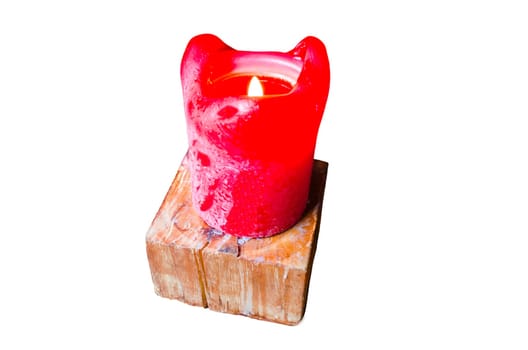 A single burning red candle on a table. Stands on a wooden candle stand. On a white background