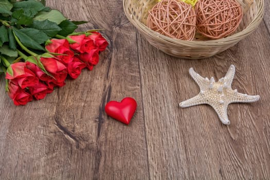White starfish, heart and red roses on a wooden background