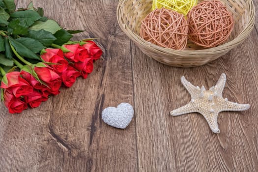 White starfish, heart and red roses on a wooden background