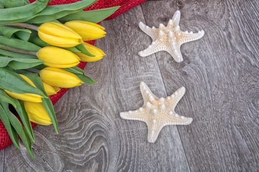 Starfishes and yellow tulips on a wooden background
