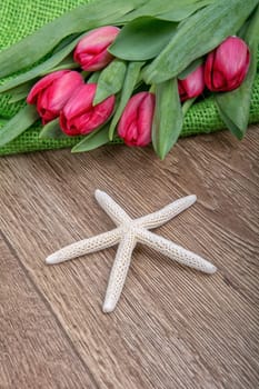 Starfish and red tulips on a wooden background