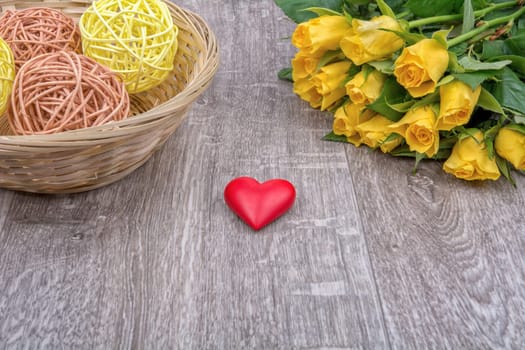 Yellow roses and red heart on a wooden background