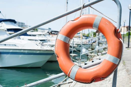 Orange life buoy hanging from a railing at the port.