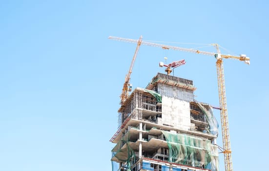 Building crane and building under construction against blue sky