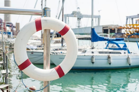 White life buoy hanging from a railing at the port.