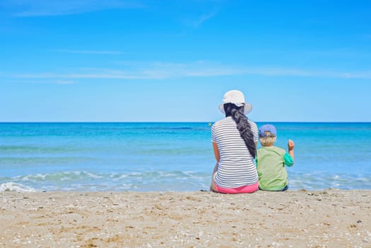 Brunette with long hair and kid turned away on the sandy beach
