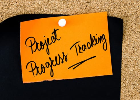 Project Progress Tracking written on orange paper note pinned on cork board with white thumbtacks, copy space available