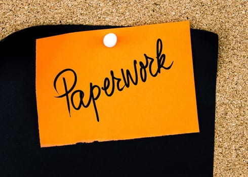 Paperwork written on orange paper note pinned on cork board with white thumbtacks, copy space available