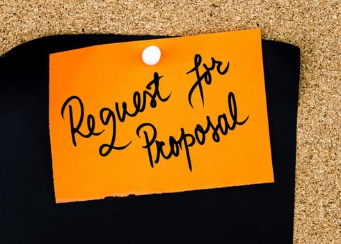 Request For Proposal written on orange paper note pinned on cork board with white thumbtacks, copy space available