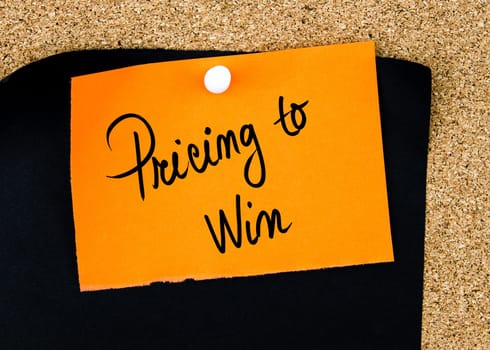 Pricing To Win written on orange paper note pinned on cork board with white thumbtacks, copy space available