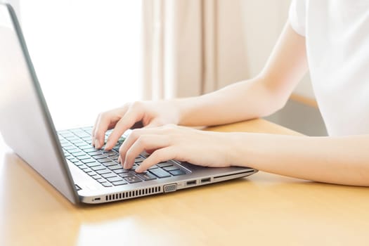Rear view of business woman hands busy using laptop at office desk, with copyspace