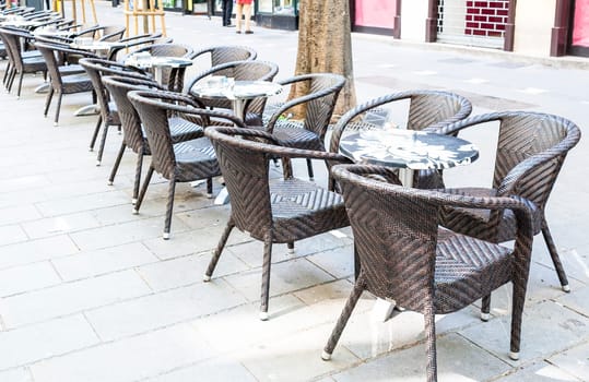 A row of small tables of a cafe on a pedestrian street