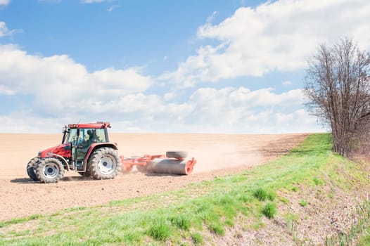 Farm work. Tractor compresses the soil after planting with rollers.