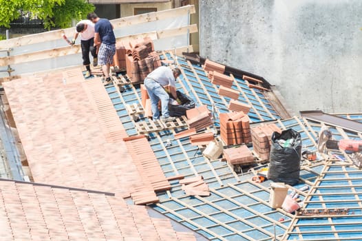 Construction site. Masons to work on the roof for laying tiles