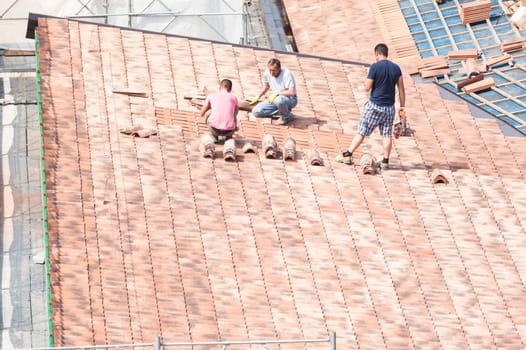 Construction site. Masons to work on the roof for laying tiles