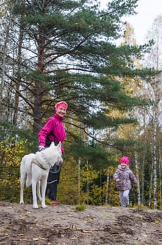 Granny with her granddaughter and a dog walk in autumn Park