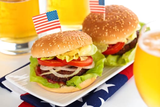 Beer and two tasty hamburgers with little American flags on top.