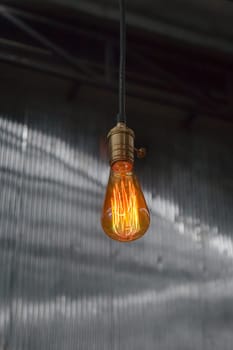 Vintage hanging light bulb over gray room, stock photo