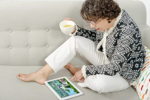 a beautiful mature woman with a tablet on the couch