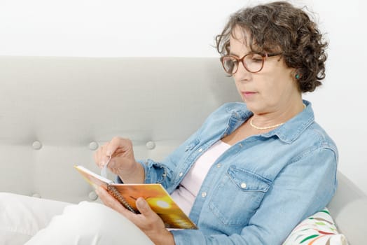 a woman of middle age reads, sitting on the sofa