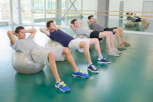 Four men exercising on aerobic balls