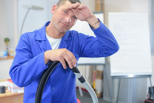 Male office cleaner wiping his brow
