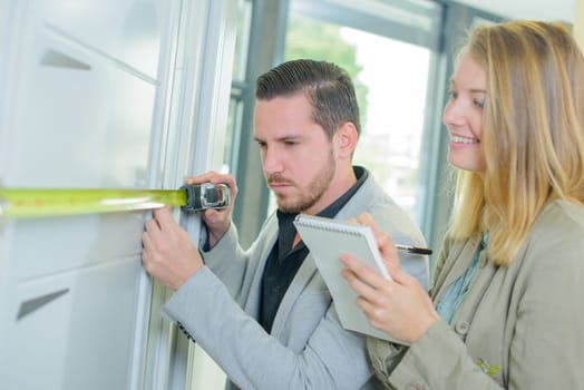 man measuring a fitted cupboard