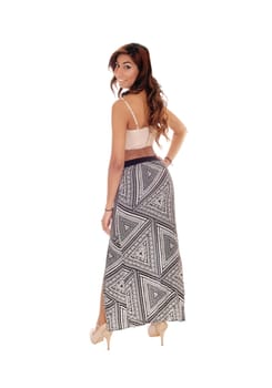 A beautiful young woman in a long skirt and short top, standing from the.back, looking over shoulder, isolated for white background. .