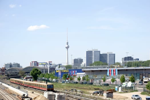 Berlin,Germany - May 09,2016: Two Berlin S-Bahn trains leave an S-Bahn station with a domed roof and the Berlin TV Tower in the background on May 9,2016 in Berlin.