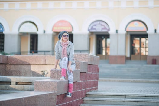 Stylish and fashionable girl on a walk around the city. Black and white knitted hat sneakers, pink socks. Outerwear, warm clothing. Fashionista. clothing items. Autumn clothes.