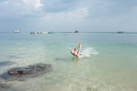 people jumping into the sea, against the backdrop of yachts, motor boats and scooters