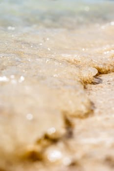 small wave of the sea, throw small, yellow sand on the beach. vertical, large, macro, bokeh