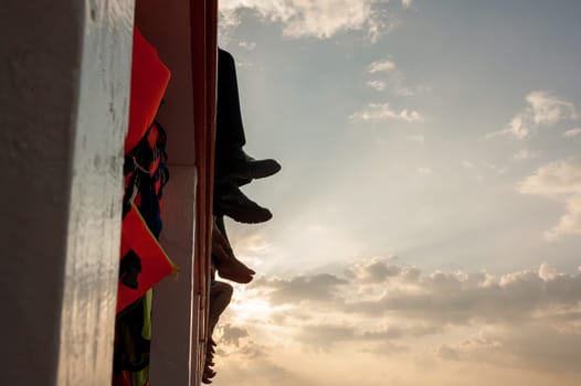 People sit on the ferry, his legs dangling over the sea. sunset, clouds, people go to work
