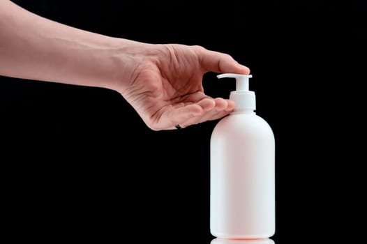 Plastic dispencer with liquid soap on a black background. Closeup