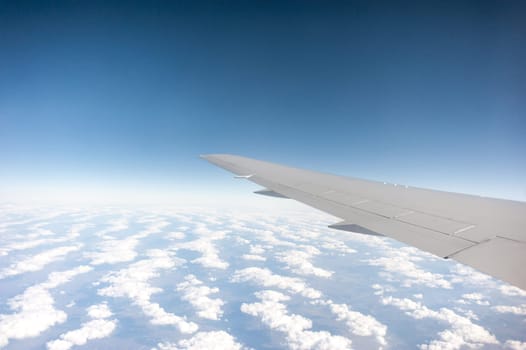 airplane wing above the clouds, blue sky