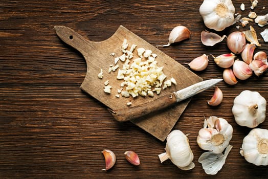 Garlic cloves and sliced garlic on vintage wooden background.