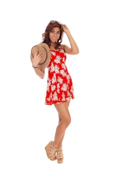A pretty young woman in a red dress and curly brown hair holding.a cowboy hat, isolated for white background..