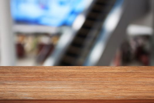 Wooden table top with blurred background of escalator in Airport
