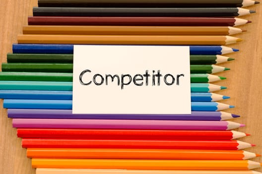 Competitor text concept and colored pencil on wooden background