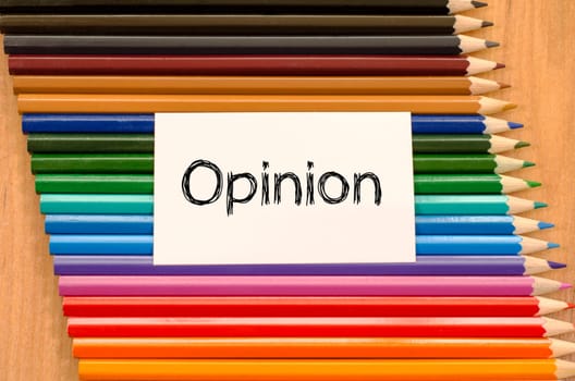 Opinion text concept and colored pencil on wooden background