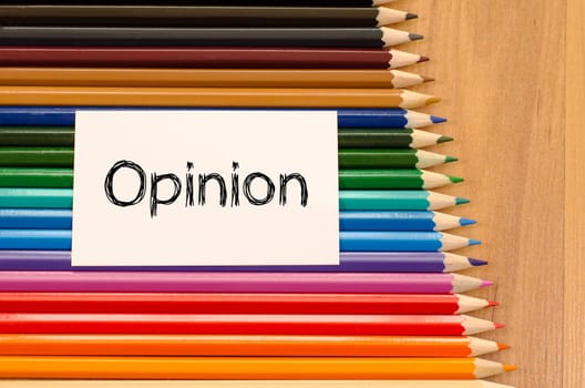 Opinion text concept and colored pencil on wooden background